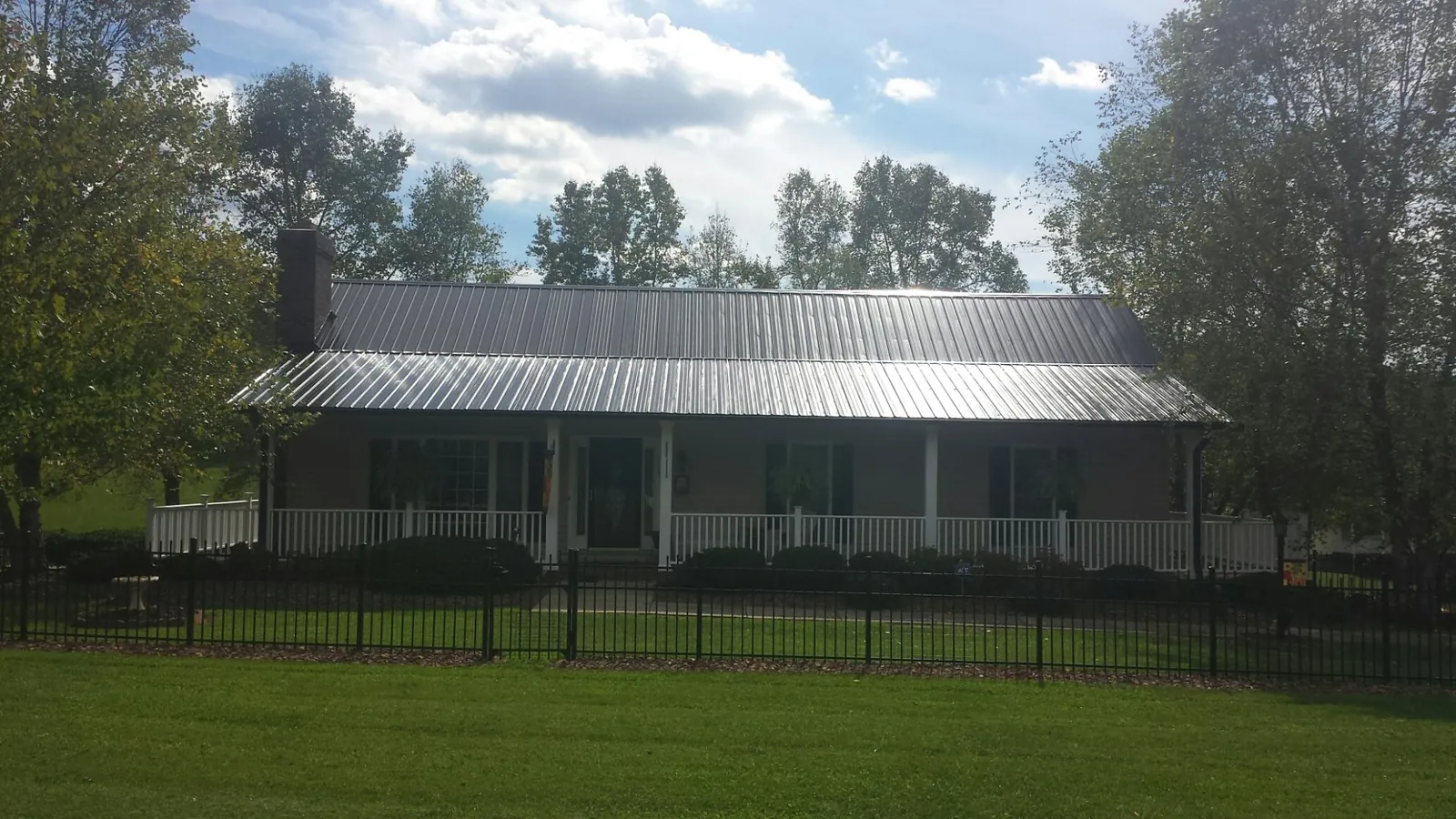 Gray metal roof on a brick ranch with a full width front porch — Gutter Guard Installation work by our crew in Weston